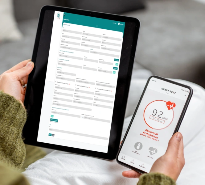 L'immagine rappresenta l'uso della **tecnologia digitale nella sanità**, mostrando una persona che utilizza un **tablet** e uno **smartphone** per gestire la propria salute da casa.  <br />Sul **tablet** è visibile una **cartella clinica digitale** o un **modulo di registrazione sanitaria**, con campi dettagliati per l'inserimento di dati personali e informazioni mediche. Il layout ordinato e il design con intestazione **verde petrolio** suggeriscono un software di **gestione sanitaria online**.  <br />Sul **telefono**, è aperta un'app di **monitoraggio della frequenza cardiaca**. Il display mostra un battito cardiaco di **92 BPM** e un avviso di **aritmia anomala**, consigliando di contattare un medico. L'interfaccia pulita e intuitiva evidenzia l'importanza della **telemedicina e del controllo remoto della salute**.  <br />L'ambiente circostante è accogliente, con **luce naturale** e un tavolino con libri e una tazza, trasmettendo un senso di relax mentre l'utente si prende cura della propria salute con strumenti digitali. <br />Questa immagine è ideale per comunicare concetti chiave come **sanità digitale, telemedicina, monitoraggio della salute, cartelle cliniche elettroniche e tecnologia per il benessere**, fondamentali nel settore della **salute digitale e del medical software**.